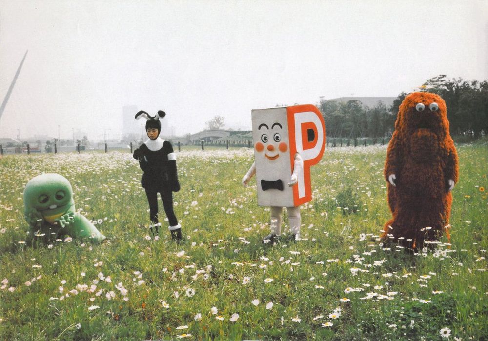 4 people in various peculiar costumes in an open field.