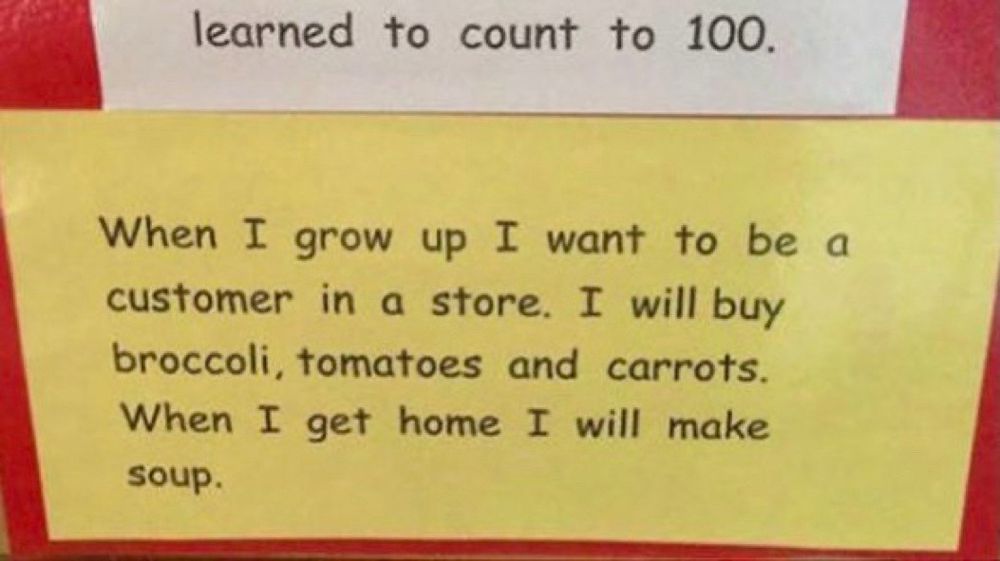 Printed on a sign on what is likely a classroom wall, “When I grow up I want to be a customer in a store. I will buy broccoli, tomatoes and carrots. When I get home I will make soup.”