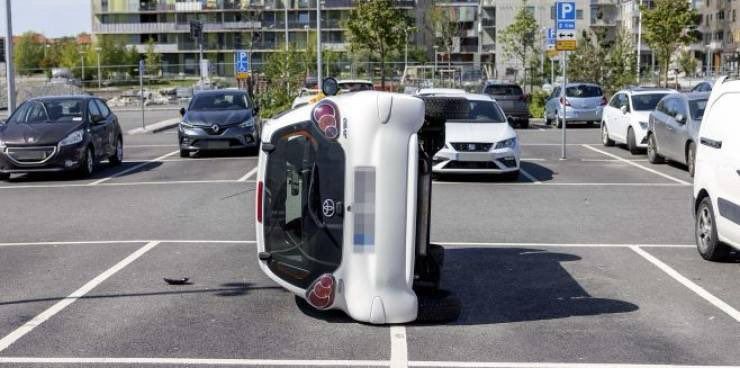 A car tipped onto its side in a parking lot.