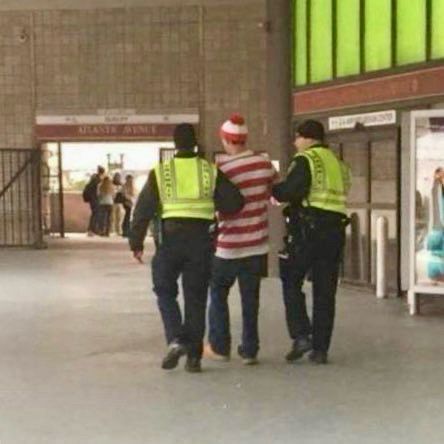 Waldo/Wally being led away by two police officers.