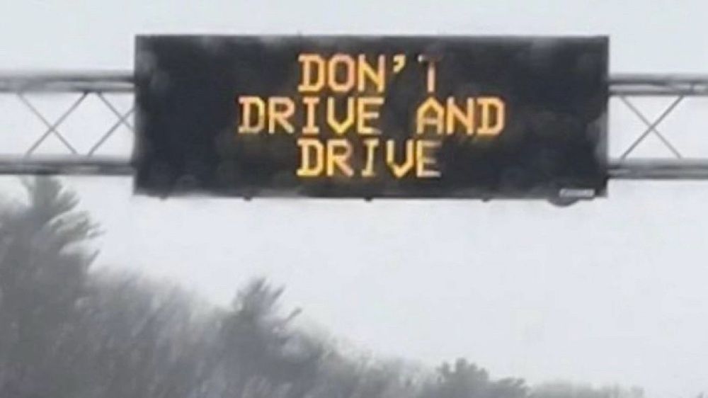 Overhead road sign reads DON’T DRIVE AND DRIVE