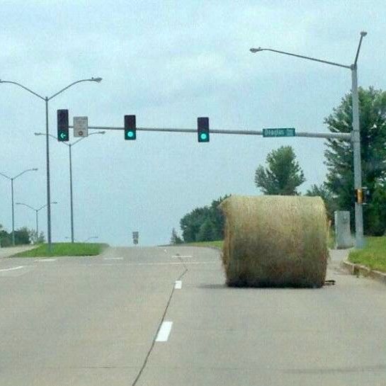 A bale of hay sits in the road at a traffic light.