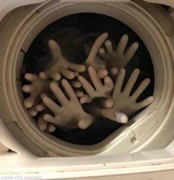 Washing machine full of rubber gloves create the appearance of hands reaching out.