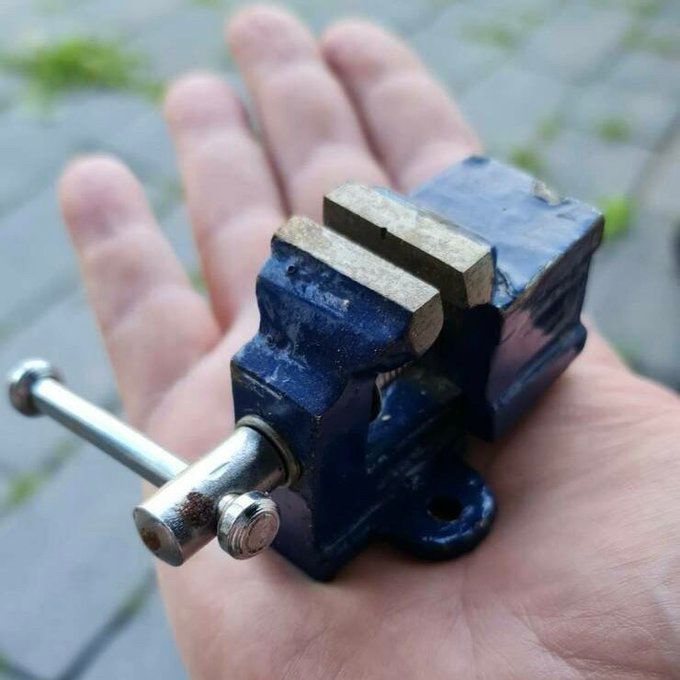 A small blue vise sits in the middle of a person’s palm. 