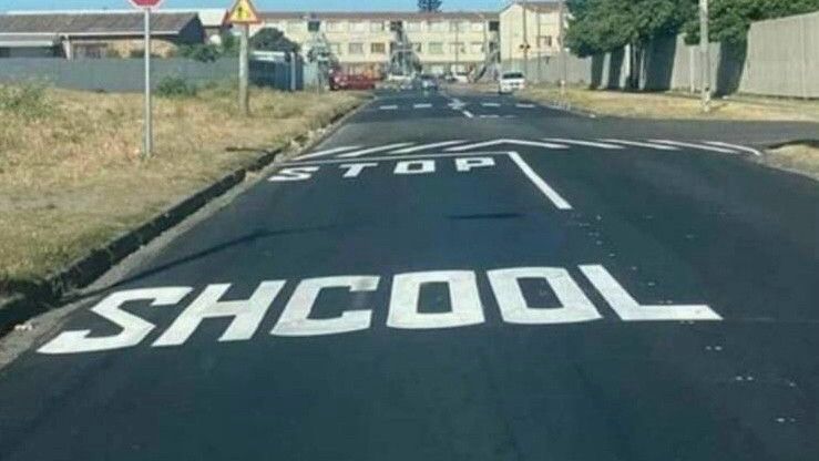 “SHCOOL” painted on roadway leading to buildings ahead.