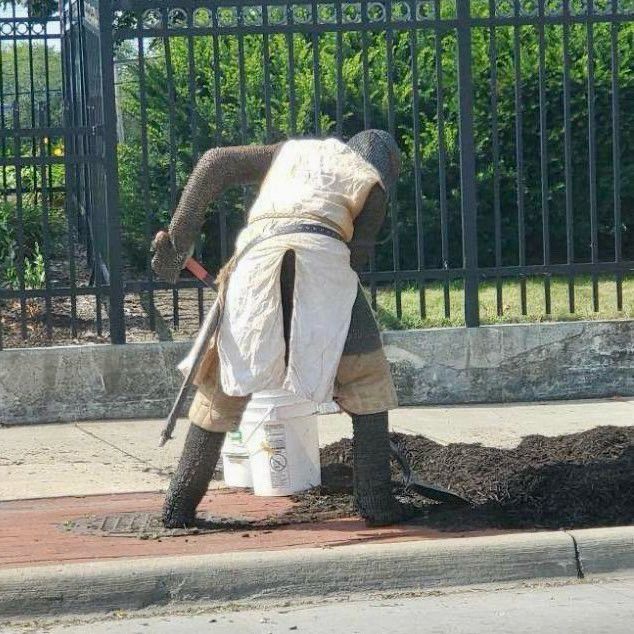 A knight shovels on a sidewalk.