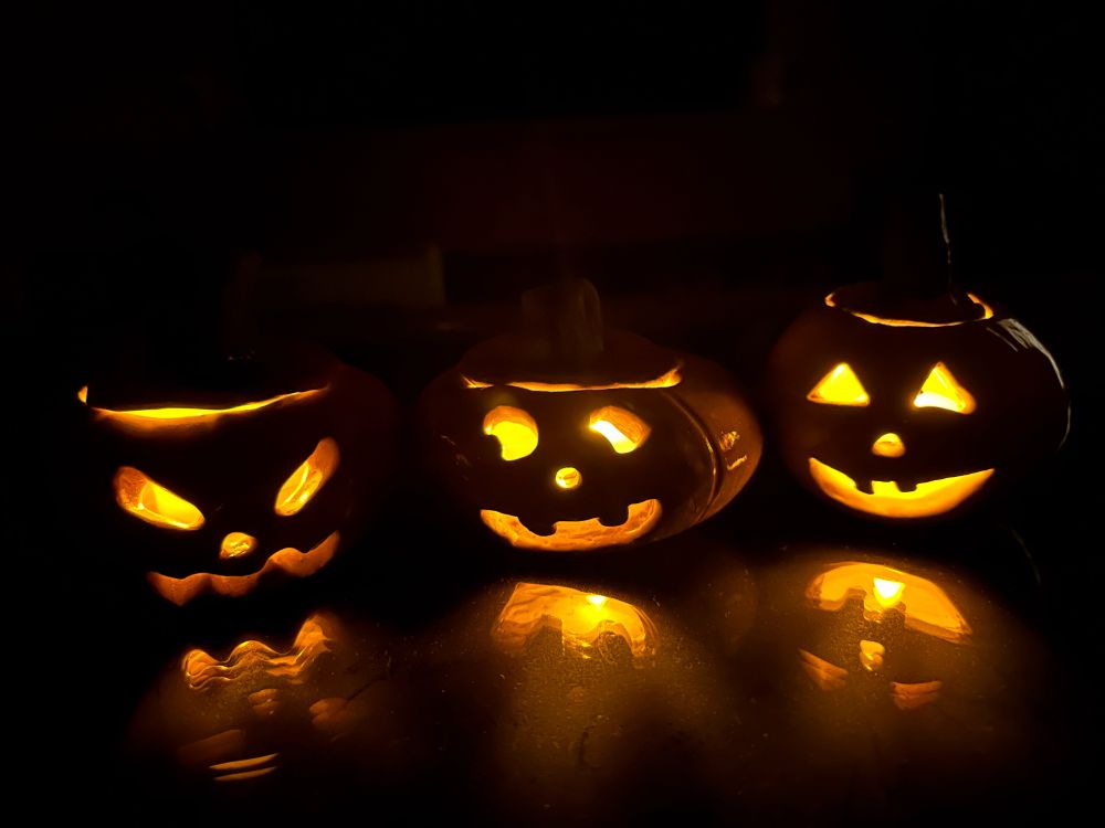 Three ceramic jack o lanterns in the dark, lit inside by fake candles. They are on a glass table so there’s a cool reflection. Very cute.