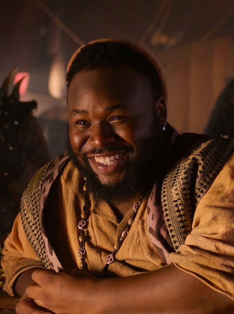 A warmly-lit screencap of oluwande smiling widely