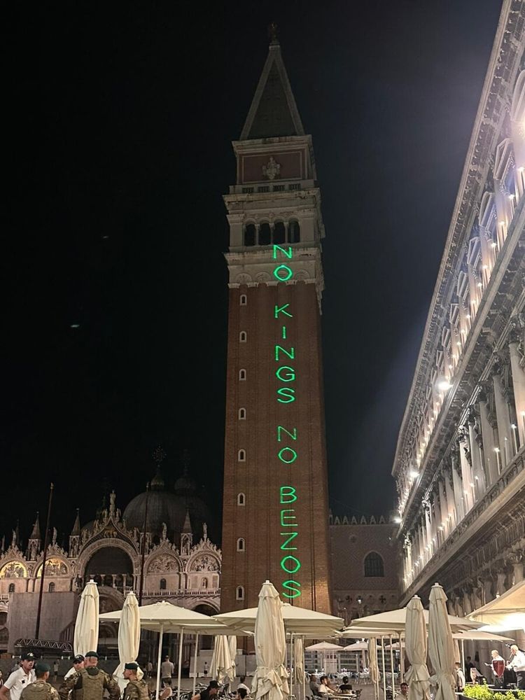 Campanile auf dem Markusplatz in Venedig in der Nacht.
Mit No Kings, No Bezos Schriftzug in grünen Buchstaben 