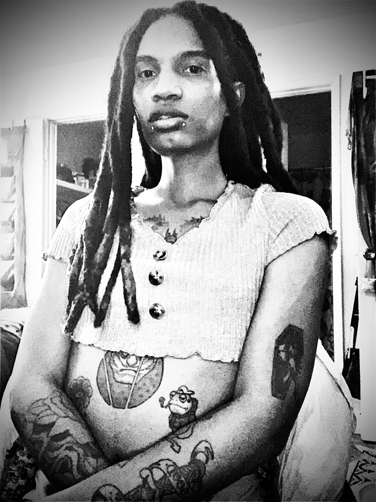 Black and white color grading photo of Tuesday in a short top with her arms loosely crossed at her belly button. 