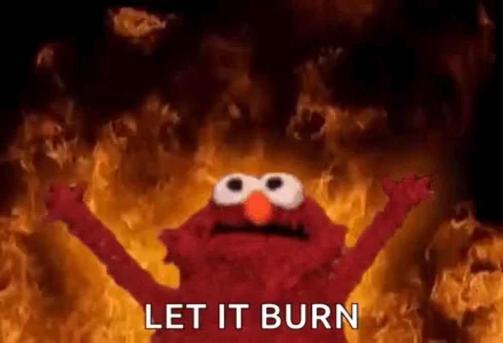 elmo from sesame street is standing in front of a wall of fire .