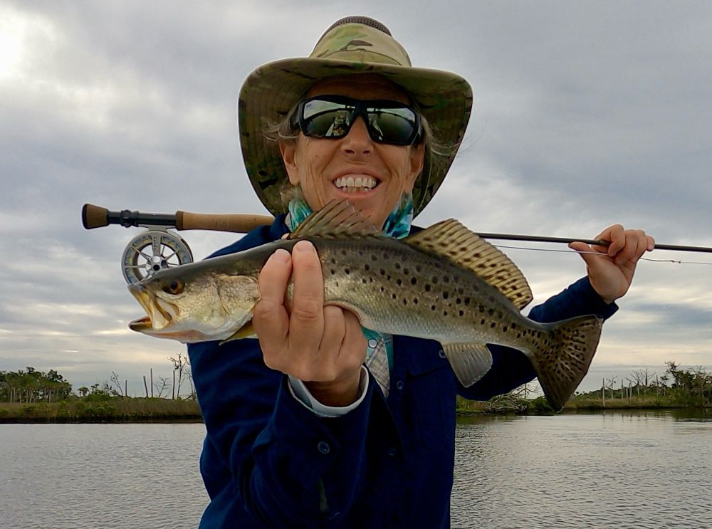 Louise with her first fish on the fly rod along with a fly she tied herself