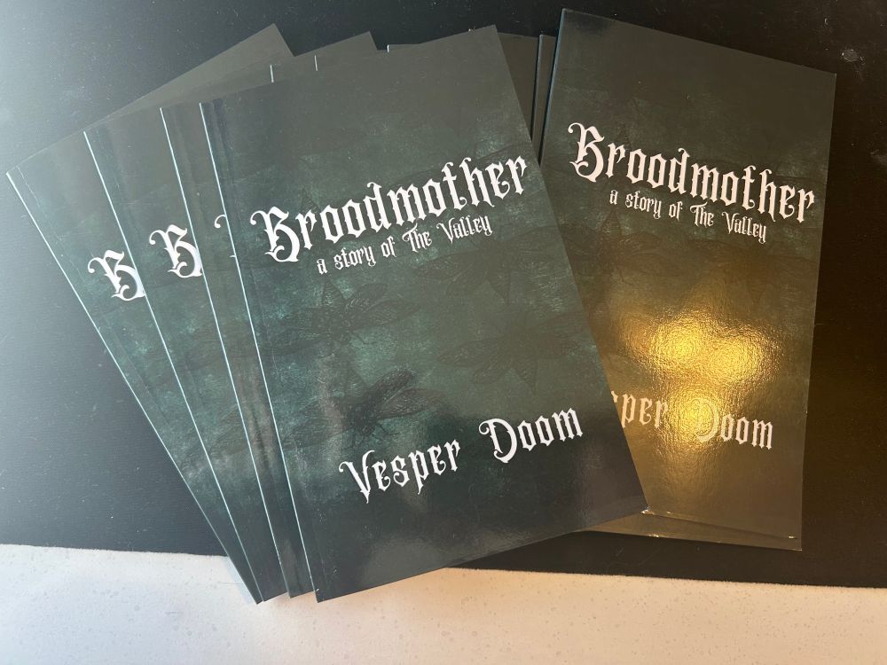 Image shows a pile of green booklets that say BROODMOTHER, A story of the Valley, by Vesper Doom