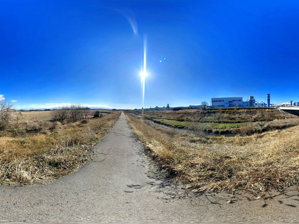 青空に太陽，川原に立ちパノラマ撮影．右手に佐野プレミアムアウトレット