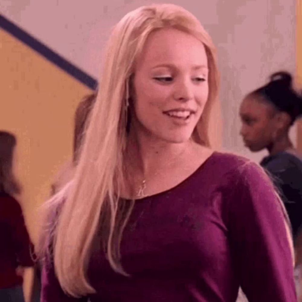 a woman with long blonde hair is wearing a purple sweater and smiling .