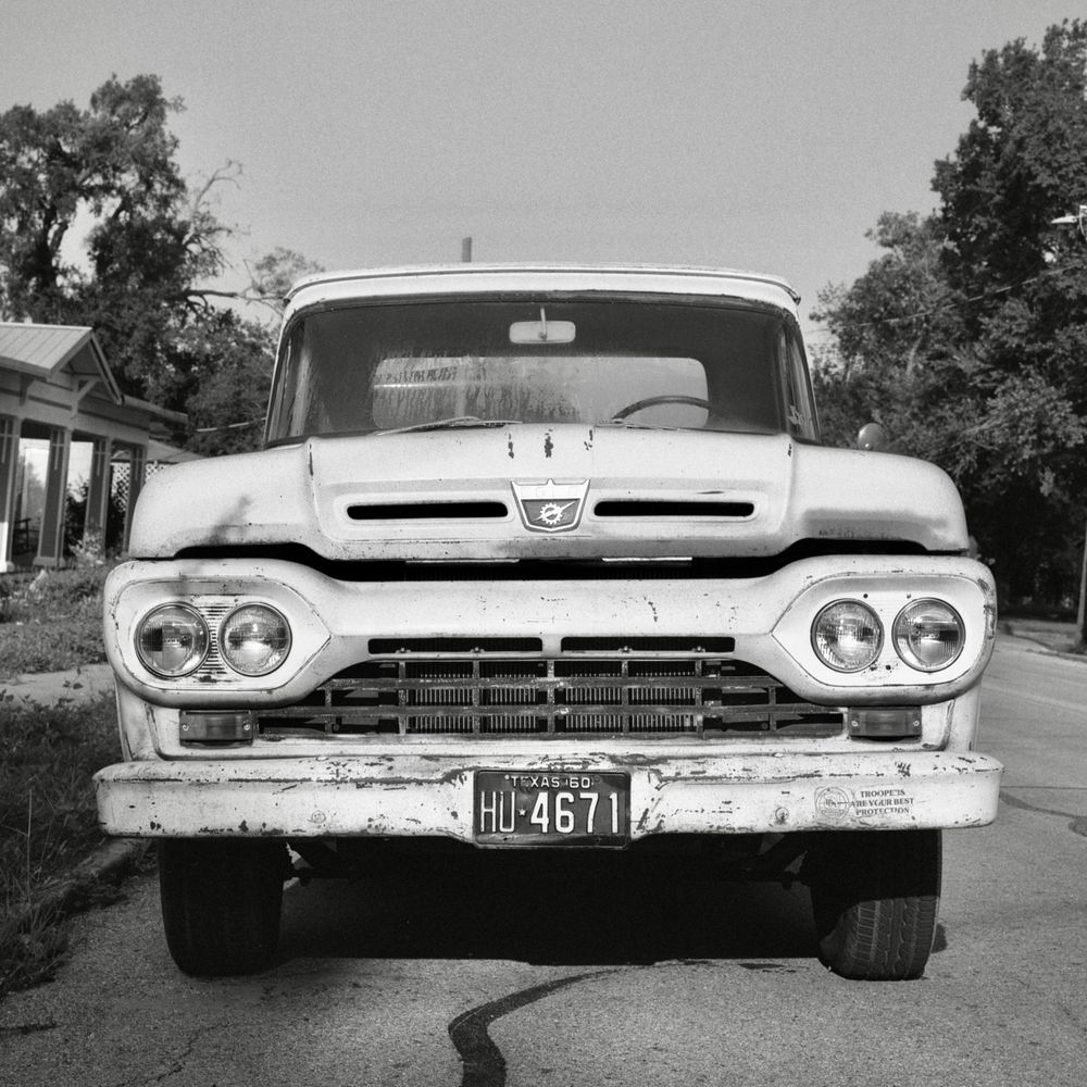 A black and white film photo. A classic 1960 Ford truck chills out on a nice sunny day in Gonzales, Texas. Sunday, June 1, 2025.