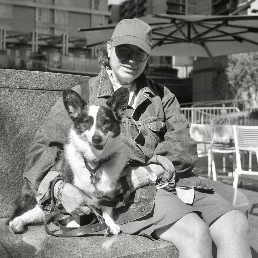 A black and white photo. Gretchen is posing with her dog Dickens in downtown Los Angeles, California. Wednesday, May 14, 2025. 