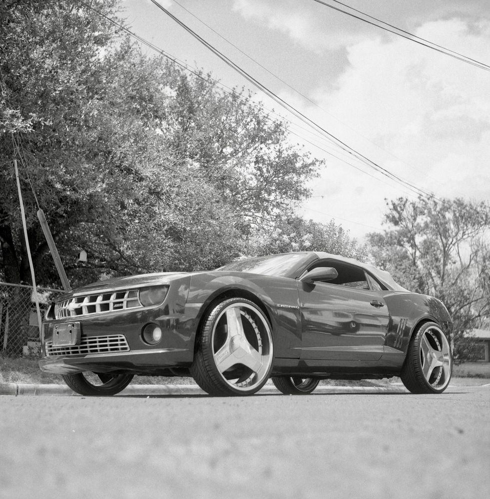 A black and white film photo. A Camaro is all shined up and ready to go for an outing later that day in Austin, Texas. Saturday, August 2, 2025.