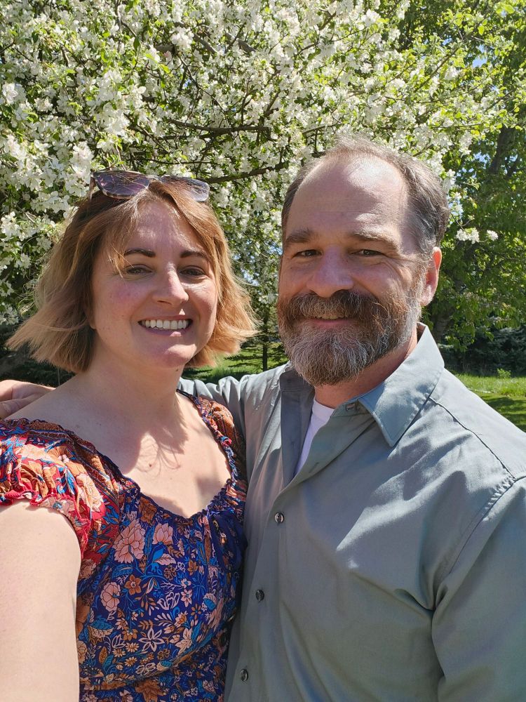 Two lovely people in front of beautiful apple blossoms. 