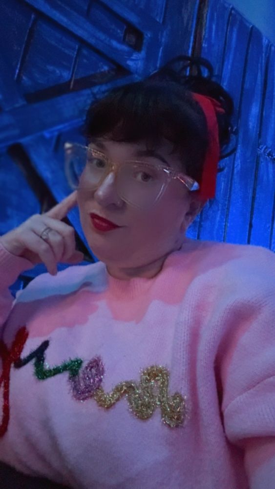 Selfie of Amanda with a red bow in her hair and pink festive sweater that says merry 