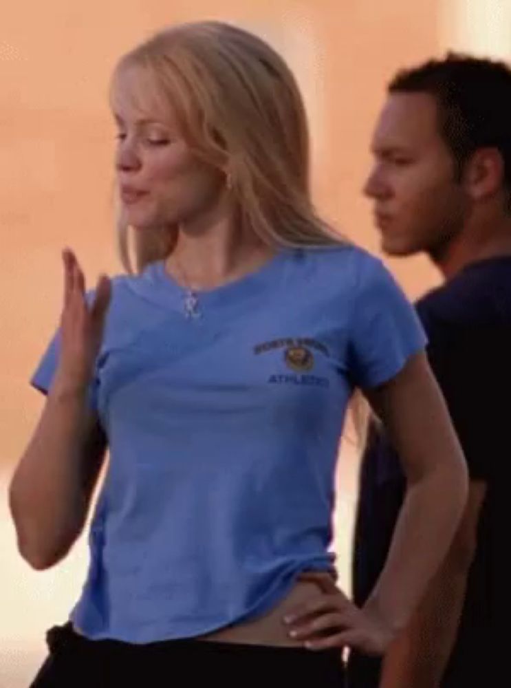 a woman in a blue shirt with the word athletics on it is standing next to a man .