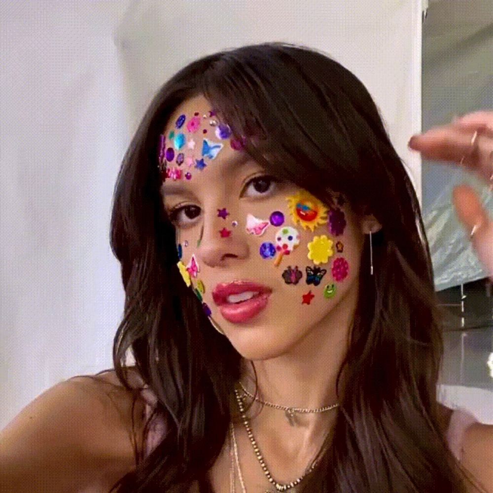 a woman with stickers on her face takes a picture