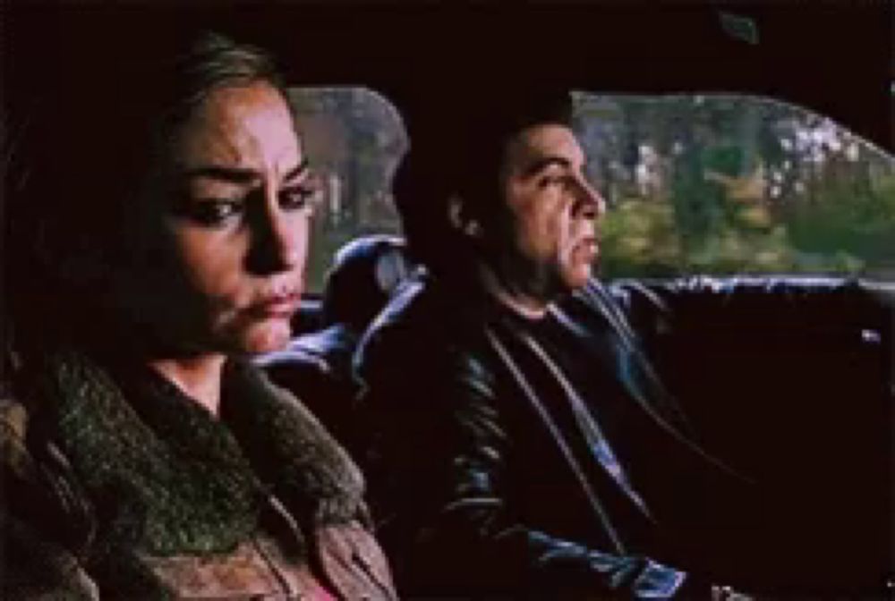 a man and a woman are sitting in the back seat of a car looking out the window