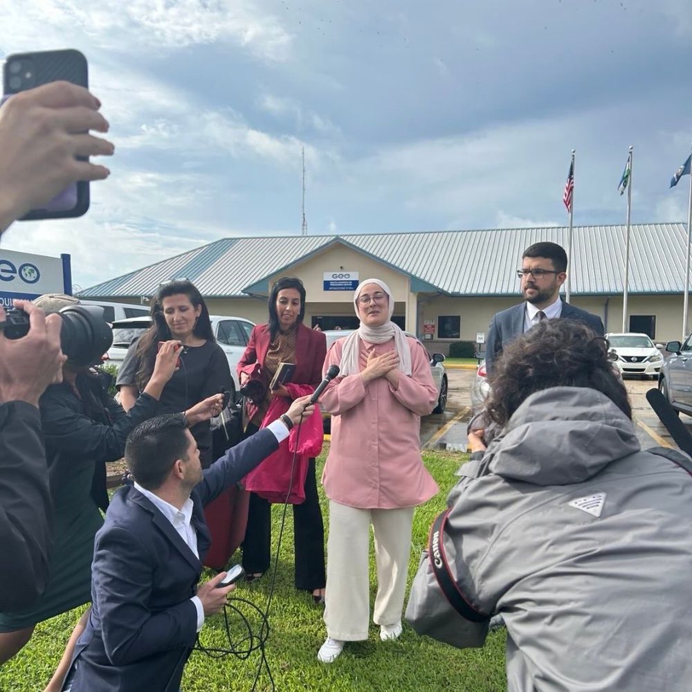 Rumeysa outside, surrounded by reporters and her team. 