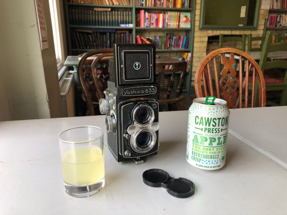 A Yashica 635 TLR camera on a cafe table with a can of Cawston Press apple juice