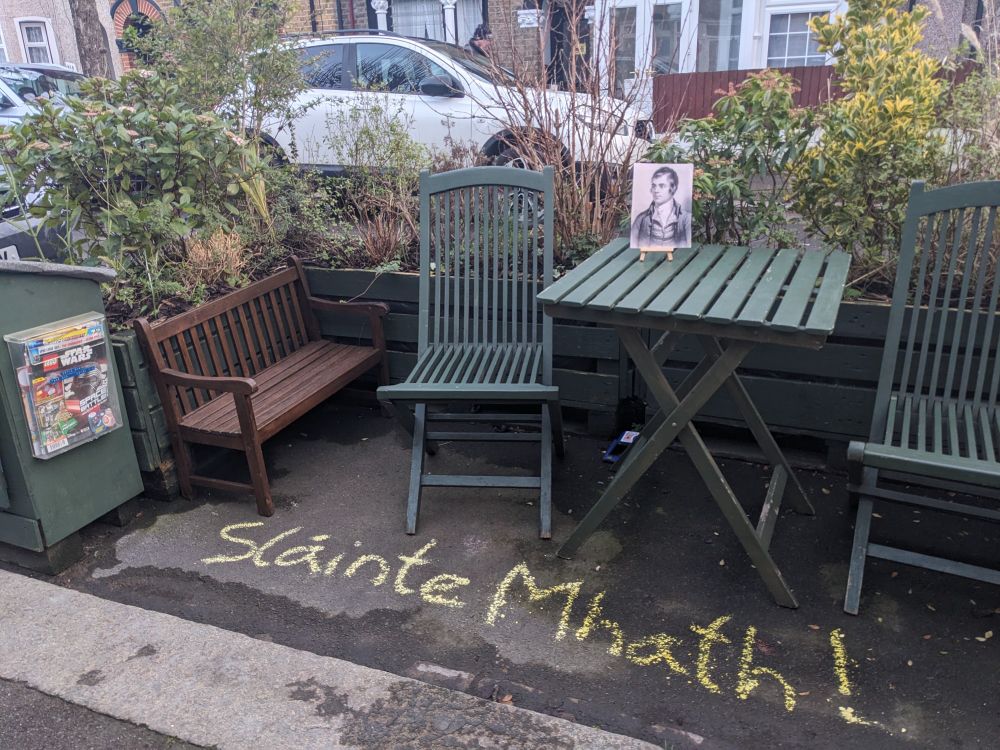 A Parklet with a picture of Robert Burns and Slainte Mhath written in chalk