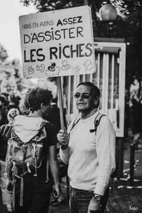 Homme brandissant une pancarte
" nous en avons assez d'assister les riches"