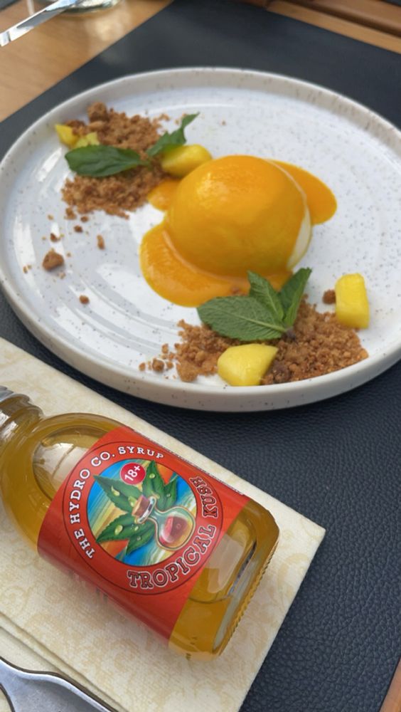 A bottle of Tropical syrup. Classic panna cotta, with mango sauce & crumble.