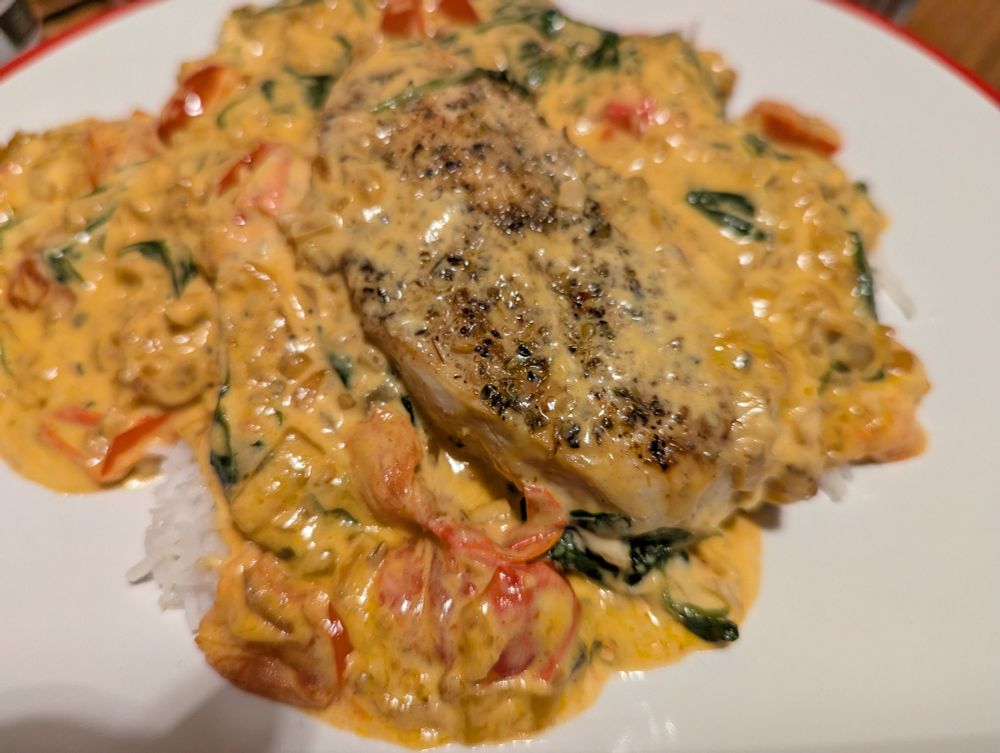 Pan fried chicken breast sitting on a bed of rice with a creamy tomato sauce