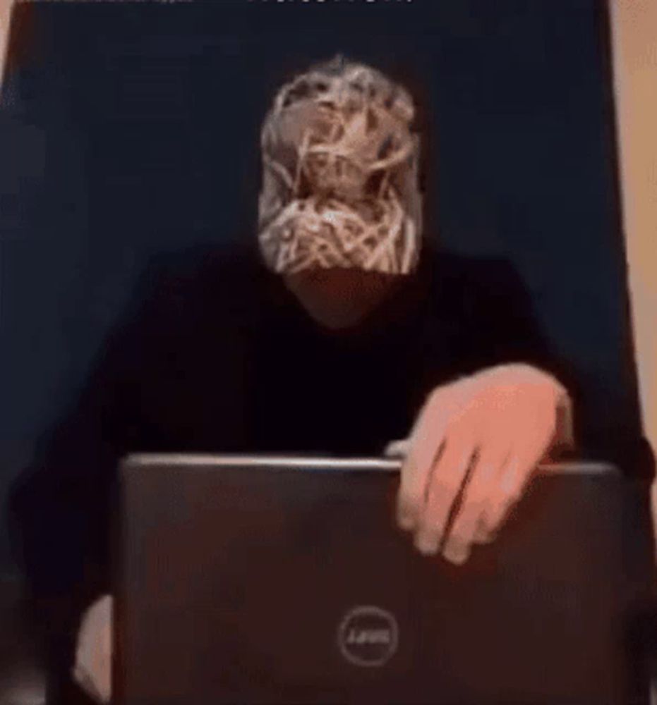 a man wearing a mask is typing on a laptop computer .