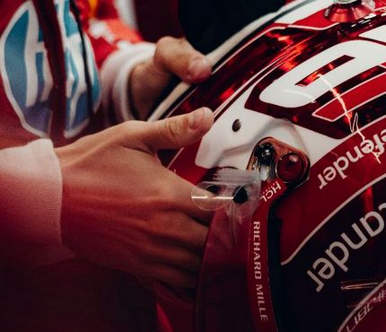 close up of charles leclerc's hands holding his helmet 