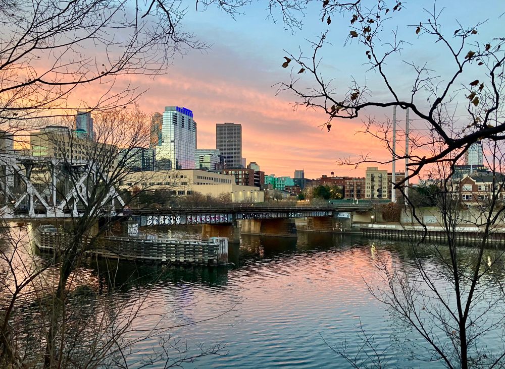 sunrise pink sky behind downtown skyline with river 
