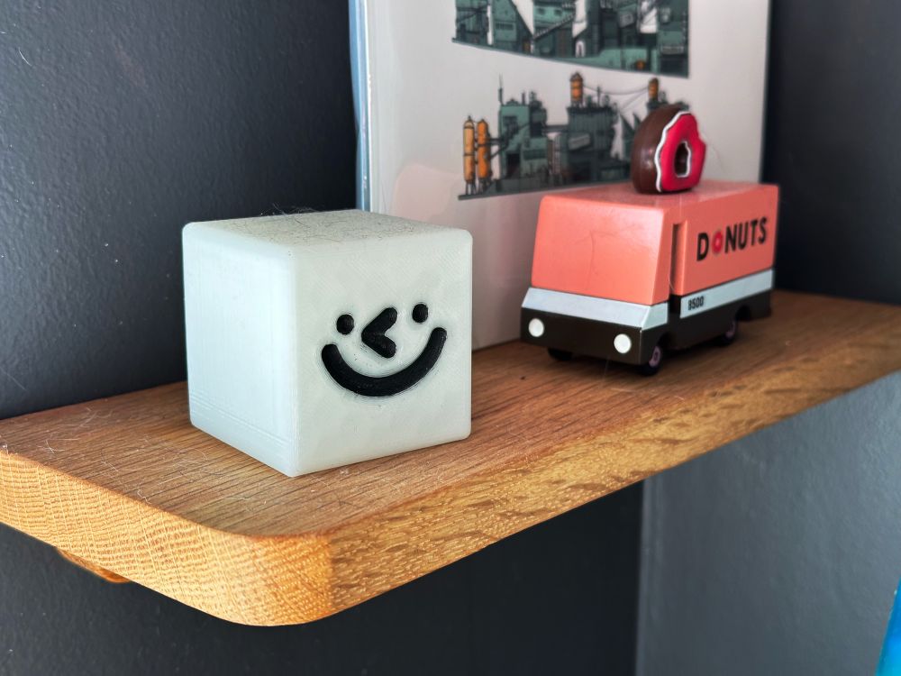 A 3D printed, glow in the dark Wilmot, sitting on a shelf.