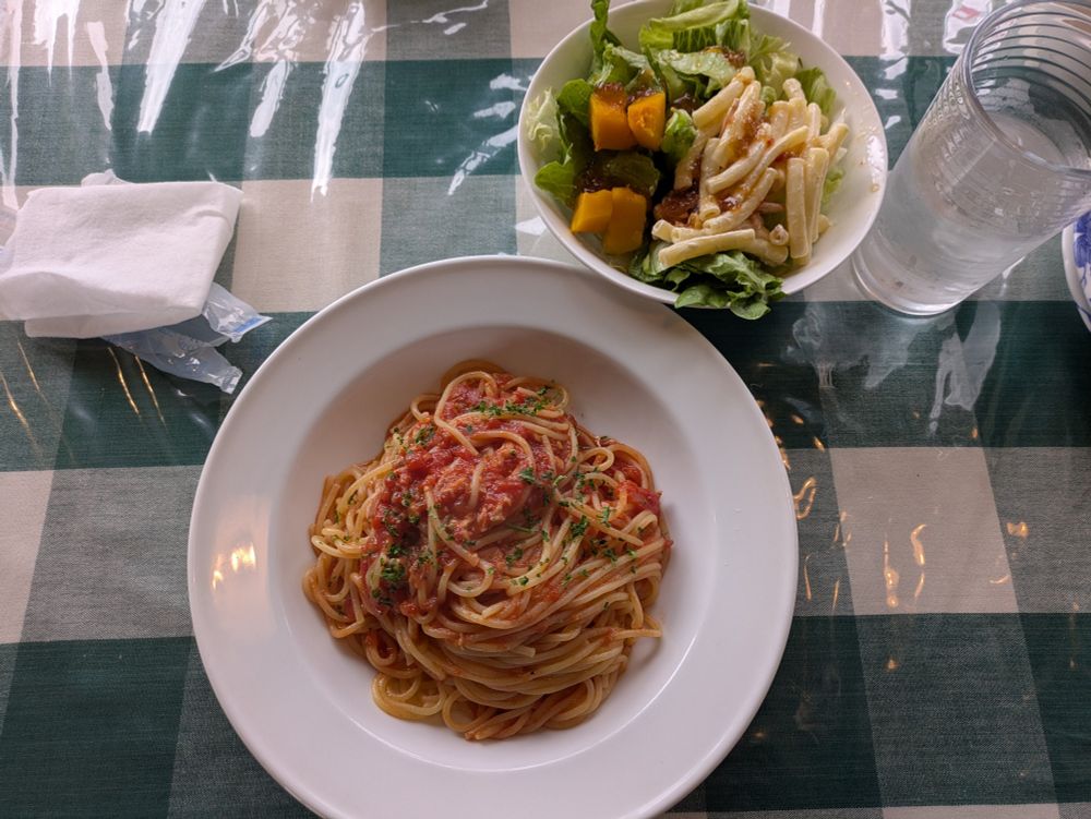 トマトツナサラダとサラダバーで取ったサラダが大盛り盛られている様子を上から撮った写真。葉物サラダにはマカロニやカボチャも乗っている。