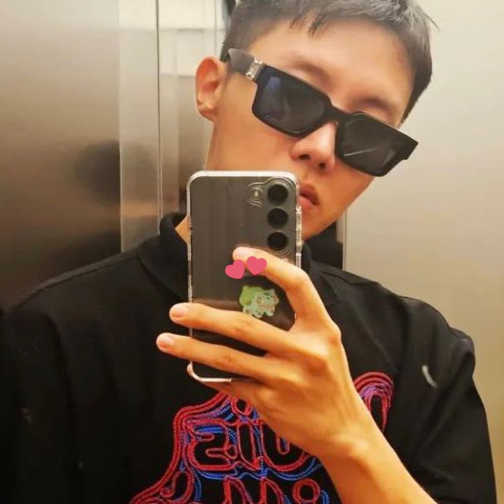 a mirror selca of hobi wearing sunglasses. on the back of his phone case is a tiny bulbasaur sticker from the pokemon bread collectible stickers. namjoon had previously uploaded a photo of his complete pokemon bread sticker binder, missing a bulbasaur.