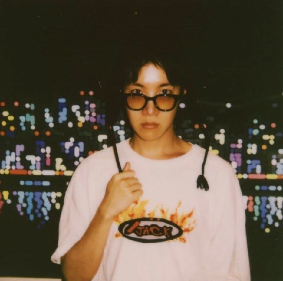 hobi standing in front of a painting by the artist yoon hyup titled seoul flow 5, an abstracted painting of city lights reflected off the han river. it was commissioned and gifted to him by namjoon.