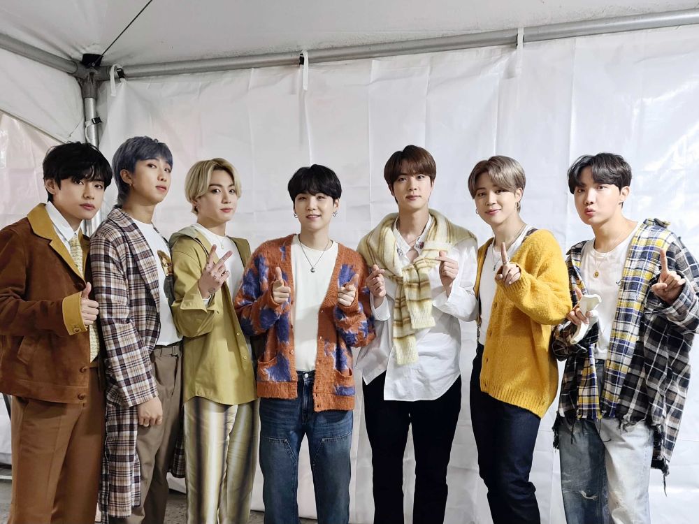 bts ot7 backstage at their 2021 golden disc awards performance. they're dressed in warm toned plaids - lots of yellow and burnt orange and some blue - and they look cozy and fuzzy and soft. yoongi is small, jungkook is blonde, jin has a sweater tied around his neck like a country club member.