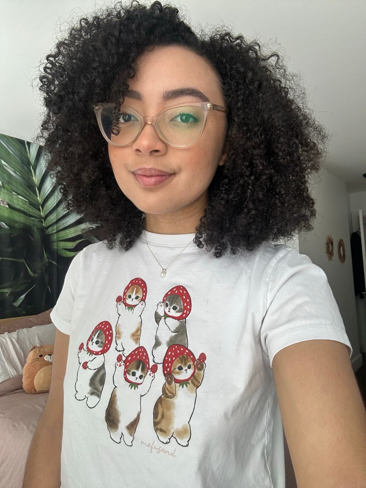 selfie of sheila wearing a mofusand graphic tee with cats wearing strawberry hats
