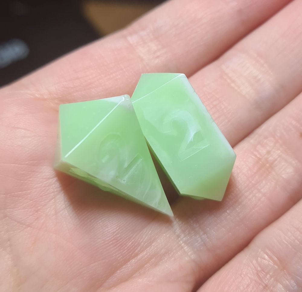 Two light green and white d4 dice on my hand