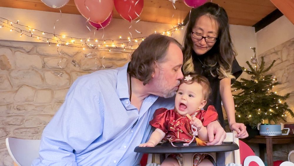 Mom and Dad kiss baby on her 1st birthday 