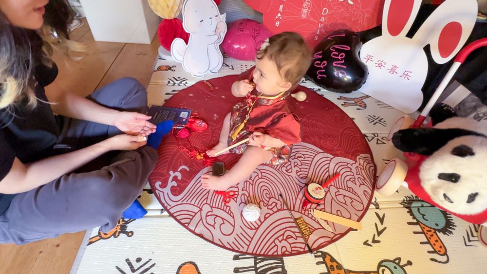 Baby plays with items representing possible life paths during Chinese “Zhuazhou” grabbing ceremony (she chose the gold ingot, representing great financial success) 