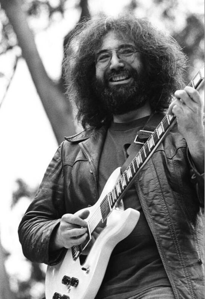 A smiling Jerry Garcia playing a guitar