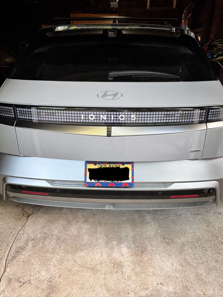The back of an ioniq5 with license plate holder that is blue with red circles. 