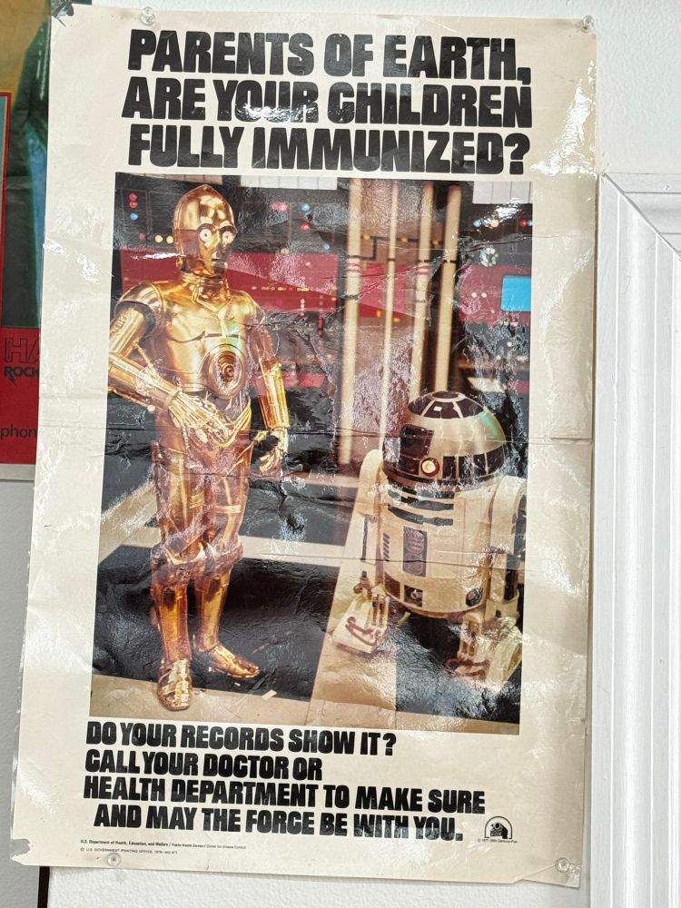 Poster of R2D2 and C-3PO working with the U.S. government. Text reads:

PARENTS OF EARTH ARE YOUR CHILDREN FULLY IMMUNIZED?
DO YOUR RECORDS SHOW IT?
CALL YOUR DOCTOR OR
HEALTH DEPARTMENT TO MAKE SURE AND MAY THE FORCE BE WITH YOU.
