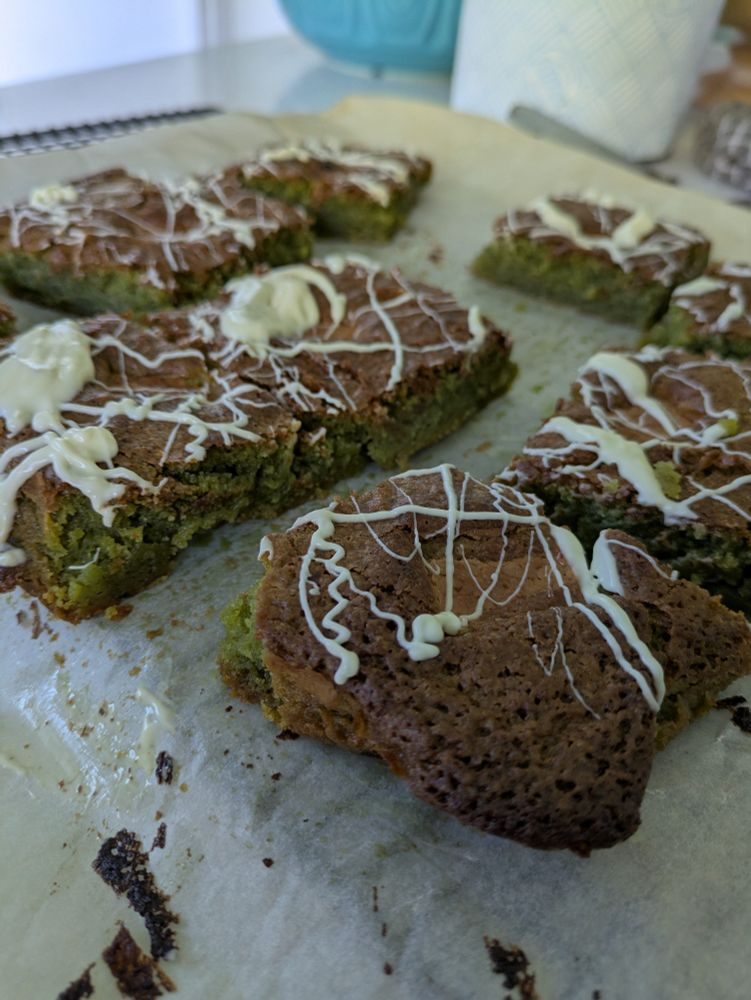 A tray of matcha blondies with a white chocolate drizzle.