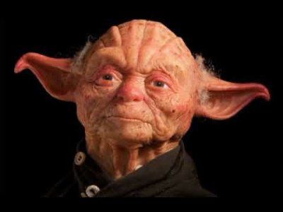 image of yoda from star wars with his skin turned white instead of green. he stares blankly forward with his mouth set in a dark shirt that nearly matches the background. 